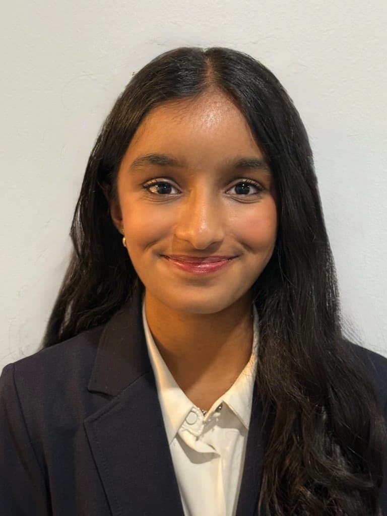 Professional headshot of Aditi Neekhra, Head of NeuroSol, smiling in a navy blazer and white collared shirt against a light background