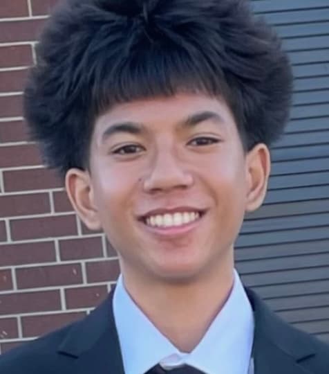 Headshot of Ethan Peters, Community Outreach Manager at NeuroSol, smiling outdoors in a dark suit and tie